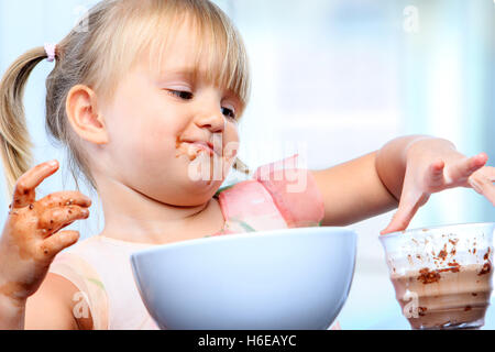 Portrait de petite fille au petit-déjeuner. Taux de répandre et de jouer avec du lait au chocolat. Banque D'Images