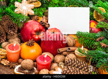 Brûler des bougies de décoration de Noël et carte de voeux. Les pommes, la mandarine, les noix, les épices et les cookies Banque D'Images