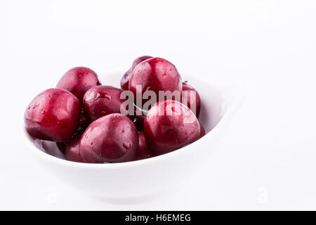Dans un bol de cerises rouges sur fond blanc Banque D'Images