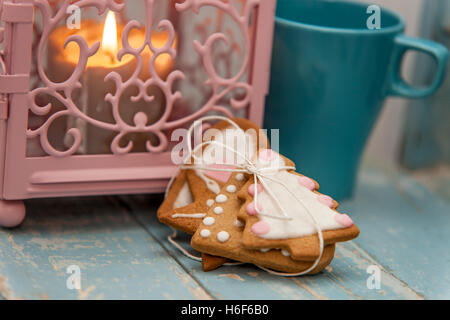 Gingerbread cookies d'hiver avec un light house bougie et un mug sur une table en bois bleu en attendant le Père Noël. Banque D'Images