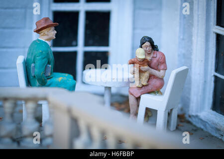 Petites figurines de famille assis sur un balcon. Banque D'Images