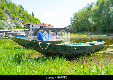 L'ancien bateau en bois avec le pont médiéval en pierre sur l'arrière-plan, Rijeka Crnojevica, le Monténégro. Banque D'Images