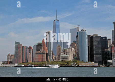 Le centre-ville de Manhattan et One World Trade Center, avec un bateau de navigation intérieure NY passant, vu de Governors Island, New York. Banque D'Images