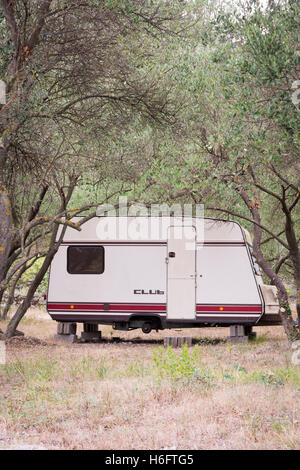 Une vieille caravane Club avec pas de roues sur briques stationné entre les arbres dans un verger en Croatie Banque D'Images