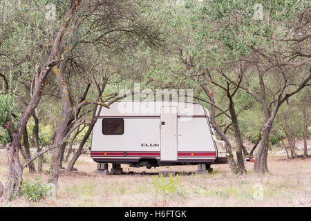 Une vieille caravane Club avec pas de roues sur briques stationné entre les arbres dans un verger en Croatie Banque D'Images