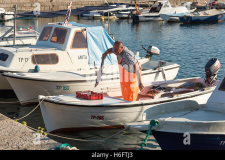 Un pêcheur décharge poisson sur un petit bateau de pêche en Trpanj Harbor Croatie Banque D'Images