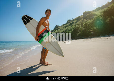 Longueur totale du jeune homme à coup de planche de surf sur la plage. Surfeur surf holding mâle au bord de la mer et à la voiture. Banque D'Images