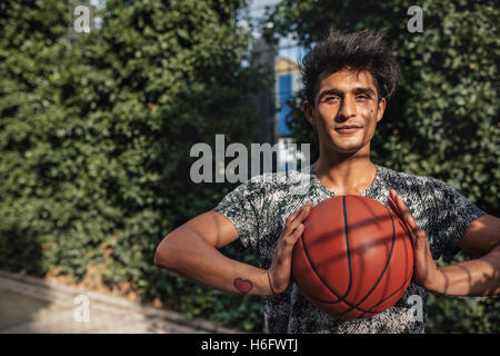 Portrait de jeune joueur de basket-ball avec une balle sur une cour. Teenage guy à propos de passer la balle. jouer streetball. Banque D'Images