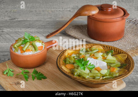 Soupe de porc aux légumes et riz, pot en céramique cuillère, sur fond de bois. Banque D'Images