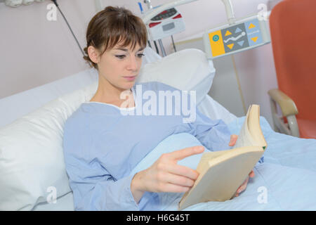 Woman Reading in hospital bed Banque D'Images