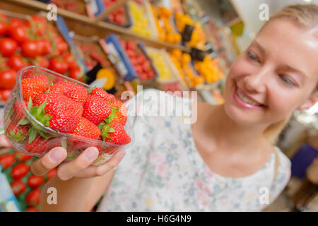 Femme blonde en choisissant quelques fraises Banque D'Images