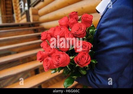 Homme avec un gros bouquet de roses. Groom tenant un bouquet de roses rouges. Banque D'Images