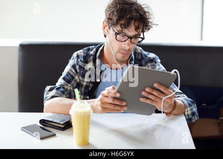 Man with tablet pc et écouteurs assis au café Banque D'Images