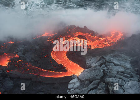 Une rivière de lave pahoehoe chaude à partir de la 61G flow, émerge d'une grotte et se déverse dans l'océan à l'entrée de l'océan, un Kamokuna Banque D'Images