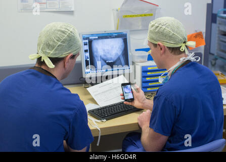 Deux médecins de discuter d'un patient X Ray sur l'écran montrant une jambe cassée.Ils discutent des images et des notes sur le téléphone mobile.