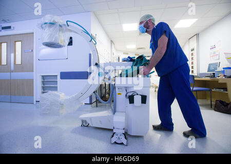 Un technicien de l'hôpital une machine à rayons X pousse le long d'un couloir Banque D'Images