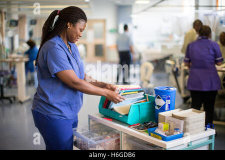 Une infirmière de l'hôpital du patient Vérification de notes sur le chariot ward Banque D'Images