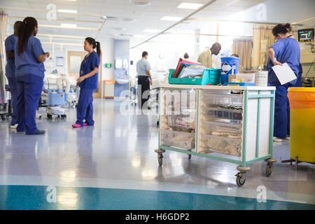 Une longue salle d'hôpital avec des infirmières avec un chariot de médicaments au premier plan Banque D'Images