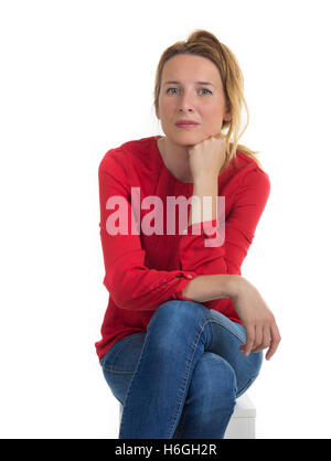 Jeune femme pensive assise sur un cube blanc en studio. Banque D'Images