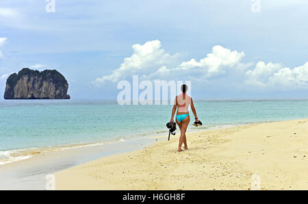 Vêtu du maillot femme marche le long d'une plage de l'île de Thaïlande, portant un ensemble de plongée Banque D'Images