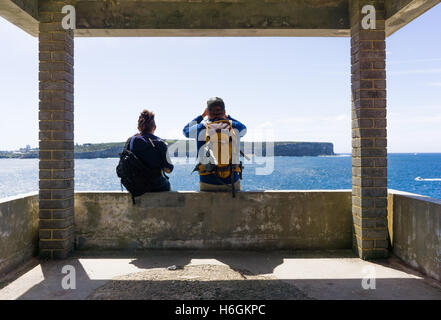 Un couple marche prendre une pause pour regarder la vue. Photographié à la tête du Sud, Sydney. Banque D'Images