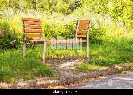 Photo horizontale intéressant de métal et bois de banc qui est placé sur la pelouse à côté du trottoir. Banc a deux Banque D'Images