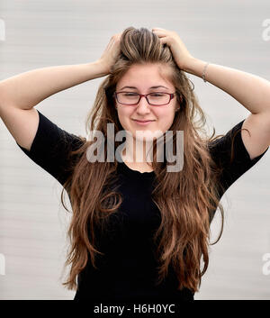 Jeune femme aux cheveux longs et portant des lunettes tout en souriant Banque D'Images