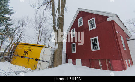 Un wagon renversé se trouve à une grange après qu'il a déraillé dans la neige lourde. Il n'y a pas de dommages à l'immeuble. Banque D'Images