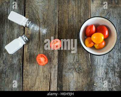 Les tomates et les salières et poivrières sur table en bois Banque D'Images