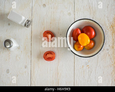 Les tomates et les salières et poivrières sur table en bois Banque D'Images