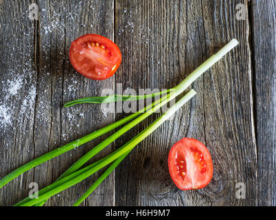 Les tomates avec les oignons verts sur fond de bois Banque D'Images