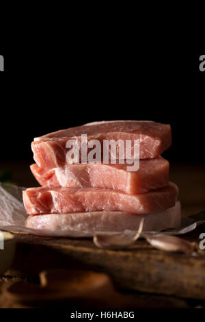 Côtelettes de porc cru prêt à cuire. Tourné en lumière tamisée. With copy space Banque D'Images