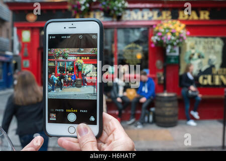 Le quartier de Temple Bar de Dublin, République d'Irlande. Une femme prend une photo en utilisant son téléphone cellulaire d'un pub. La région est un l Banque D'Images