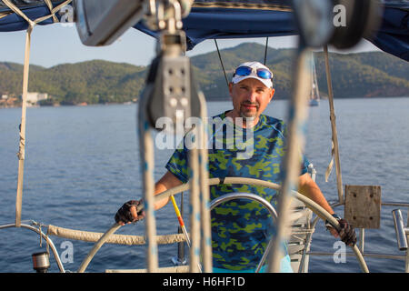 L'homme dirige les commandes d'un yacht à voile. Banque D'Images