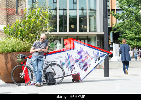 Un homme se reposant à l'extérieur de la gare de Kings Cross à King's Cross, Londres, Royaume-Uni. Banque D'Images