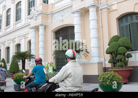 Les vietnamiens sur les scooters vélos équitation passé l'Hôtel de Ville bâtiment du Comité populaire de Ho Chi Minh ville, Saigon, Vietnam Banque D'Images