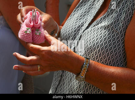 Panier en osier plein de baby bootie handmade tricoté par une vieille dame dans une rue arrière à Sorrente Italie paires mixtes rose bleu peg Banque D'Images