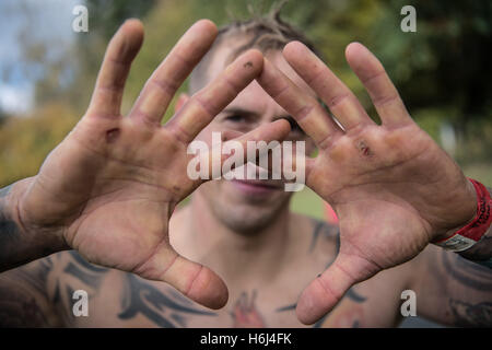 Waechtersbach, Allemagne. 29 Oct, 2016. Benjamin Rabe est avec des cloques sur les mains juste avant la ligne d'arrivée à la variante du marathon fer 'Viking' la concurrence dans Waechtersbach, Allemagne, 29 octobre 2016. Les participants doivent remplir un jusqu'à 42 km, avec plus de 100 cours d'obstacles, au cours de laquelle ils doivent ramper dans la boue, les douves, tirer les troncs des arbres, et descendre un toboggan géant où ils atterrissent dans une boue mis à l'eau glacée pendant les 'Fjord Dump." Photo : BORIS ROESSLER/dpa/Alamy Live News Banque D'Images