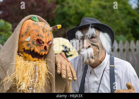 Merrick, New York, USA. 29 Oct, 2016. À droite, Jim Johnson, de Merrick, vêtu d'un costume de Munchkin Wizard of Oz, se tient devant sa cour décorée dans un effrayant spooky Wizard of Oz thème, à divertir les gens comme ils marchent dans la rue à l'entrée de parc Fraser pour l'année 2016 Grimaces dans Merrick a accueilli en partie par le nord et le centre de l'Association civique Merrick (NCMCA). JOHNSON'S main reposait sur un homme de paille horrible, macabre décoration pelouse, avec un daggner plongé dans sa tête de citrouille. © Ann Parry/ZUMA/Alamy Fil Live News Banque D'Images