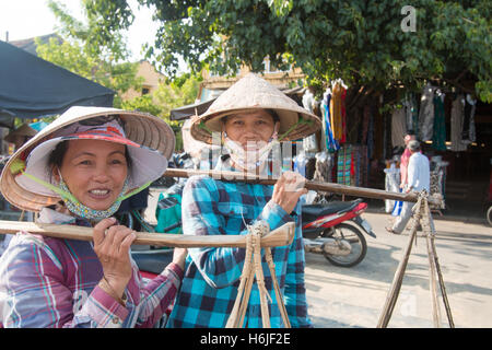 Deux femmes vietnamiennes à Hoi An assorties chacune d'un joug de bambou portant des fruits à vendre,Hoi An,le Centre du Vietnam Banque D'Images
