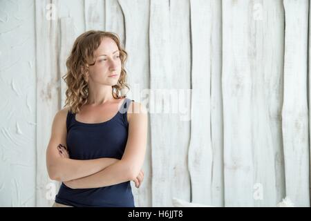 Belle Jeune femme debout avec les bras croisés contre le mur gris