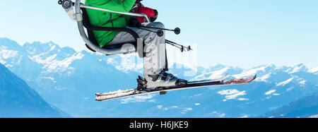 Skieurs sur télésiège avec les montagnes enneigées en arrière-plan Banque D'Images