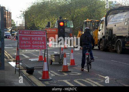 Cycliste avec feux de circulation temporaires et travaux routiers sign Banque D'Images