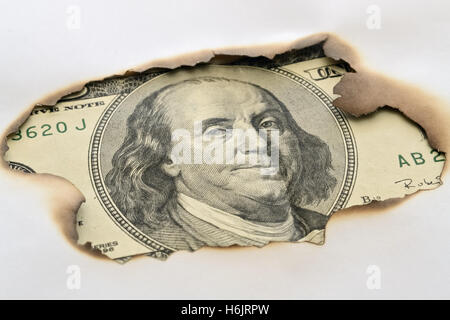 Des billets de cent dollars placés sous papier brûlé Banque D'Images