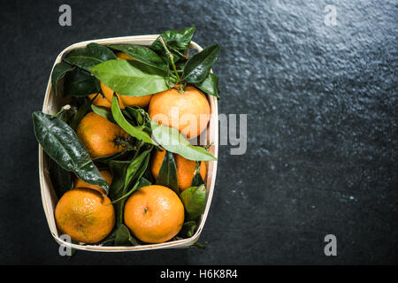 Boîte en bois avec de la mandarine avec des feuilles Banque D'Images