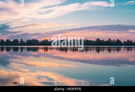 Matin coloré lever du soleil reflétée dans les eaux du lac clair miroir Banque D'Images