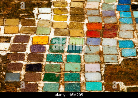 Extreme close up of colorful endommagé vintage vieux négligé pour mosaïque et textures sur sable rouge Chemin de jardin en plein air Banque D'Images