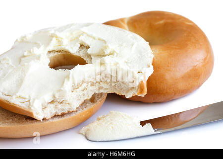 Bagel nature avec couteau, tartiner avec le fromage à la crème et en-cas manquants. Banque D'Images