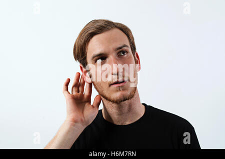 Un jeune homme adulte portant des T-Shirt avec sa main près de son oreille, les jeunes adultes de sexe masculin Banque D'Images