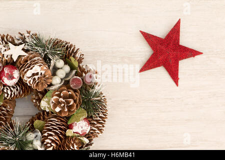 Couronne de Noël délicate de cônes de pin et une étoile rouge sur fond de bois gris Banque D'Images